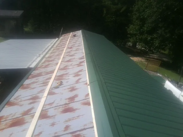 Old rusted panels beside newly installed green metal roofing — Wind Damage Roof Repair by Roofing Brothers in Acton