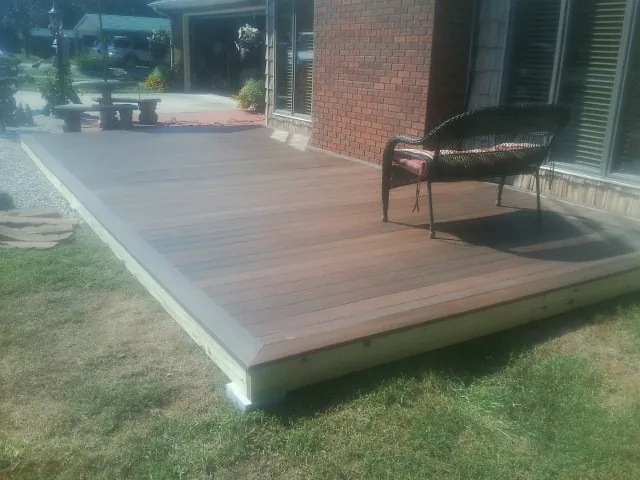 New wood deck and wicker chair beside a brick house in Acton