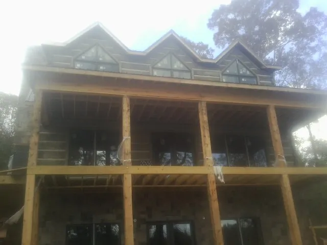 Dormers and porch framing on a large log home under construction — Roof Coating work by our crew in Acton