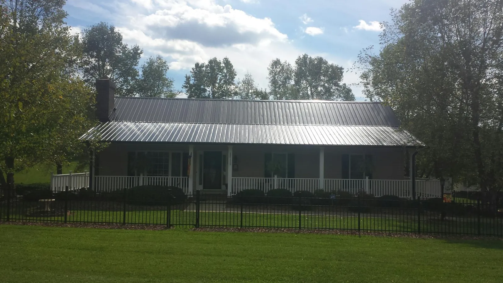 Gray metal roof on a brick ranch with a full width front porch — Gutter Guard Installation work by our crew in Acton