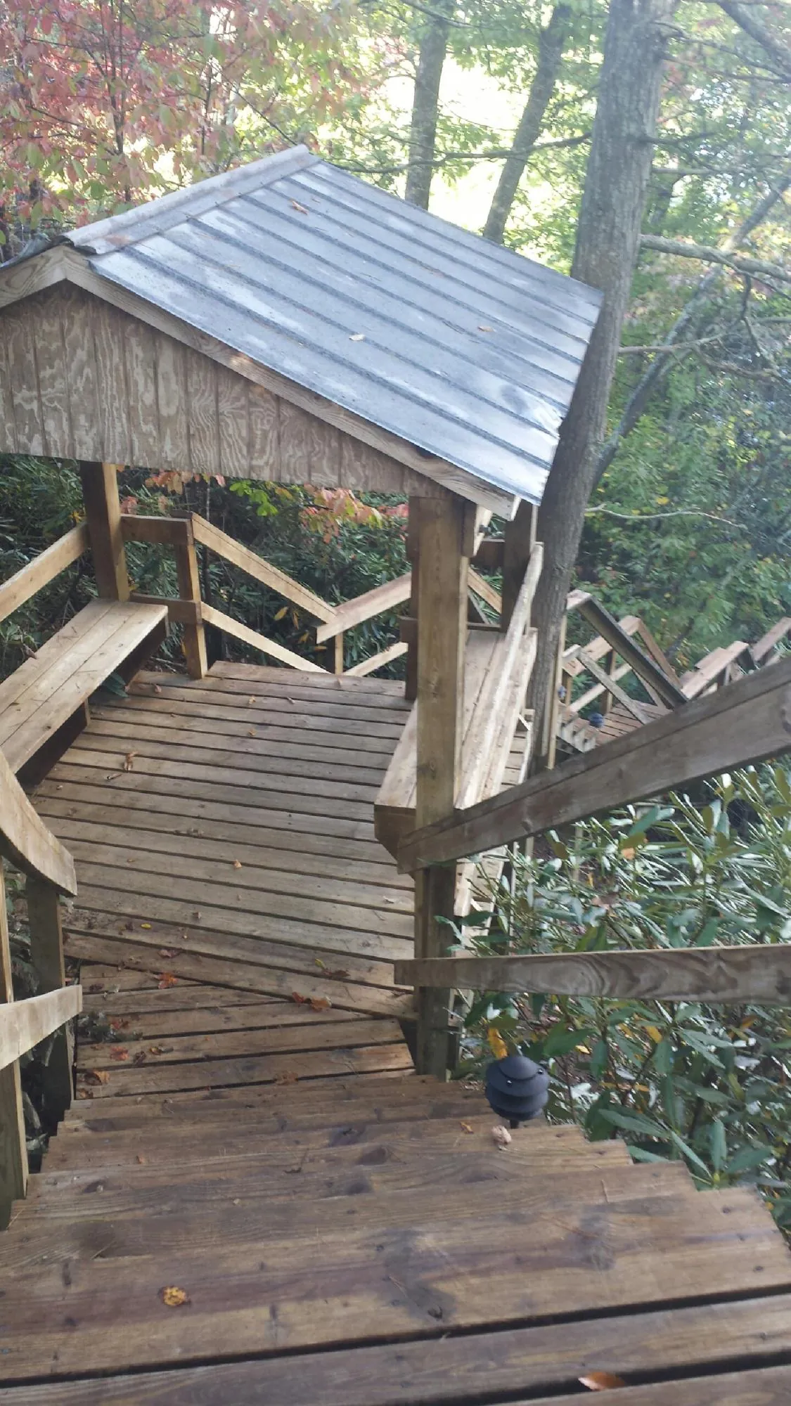 Metal roofed shelter over wooden steps on a wooded walkway — Skylight Repair & Installation work by our crew in Acton
