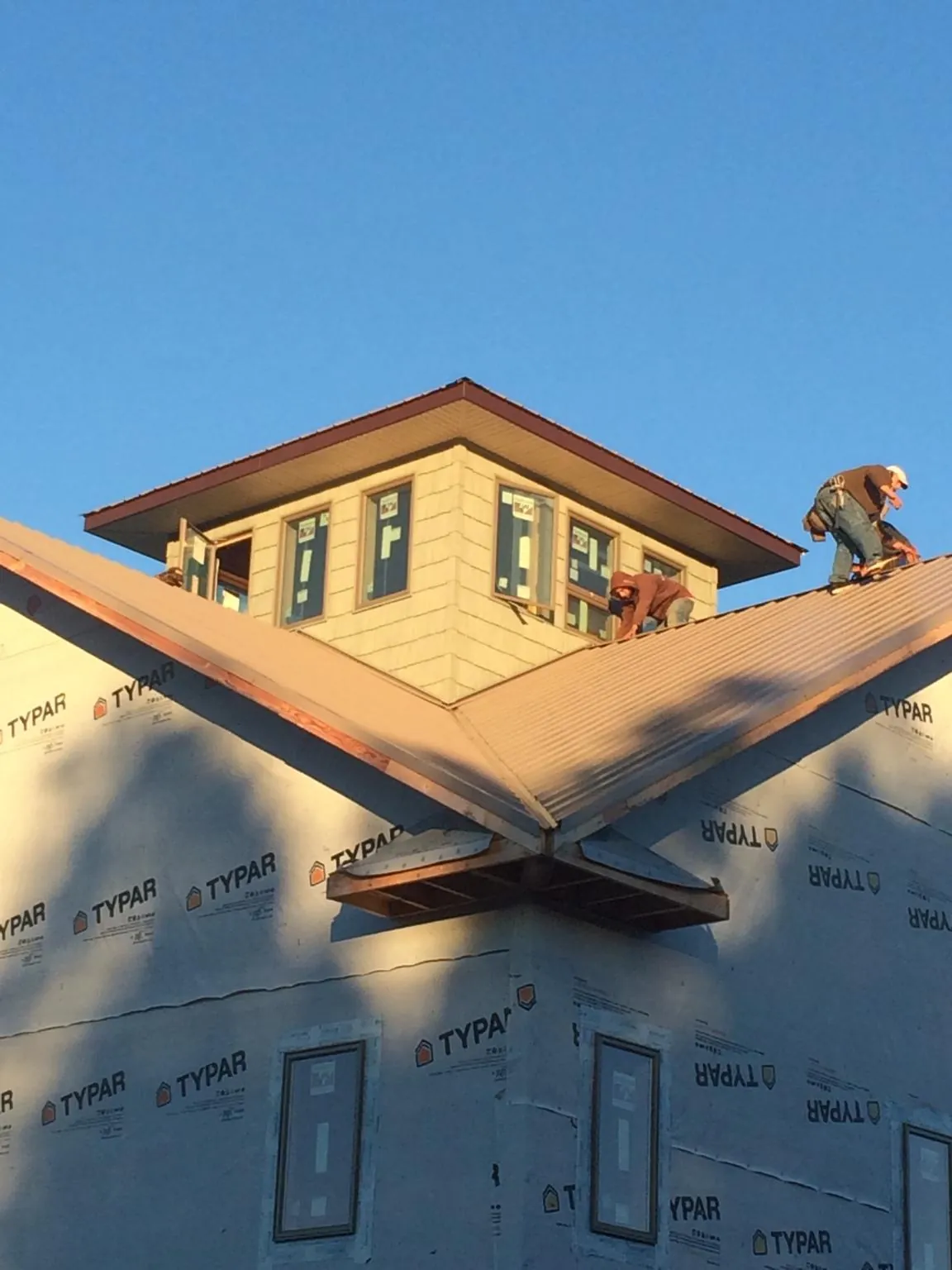Roofers working around a rooftop cupola on a new metal roof at sunset — Roof Waterproofing in Acton by Roofing Brothers